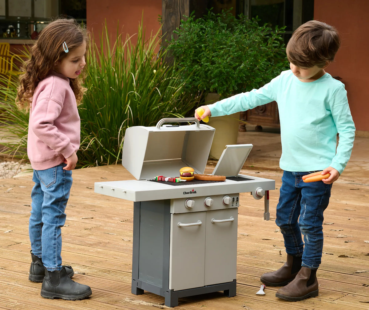 Two children grilling pretend food on a Char-Broil toy barbecue